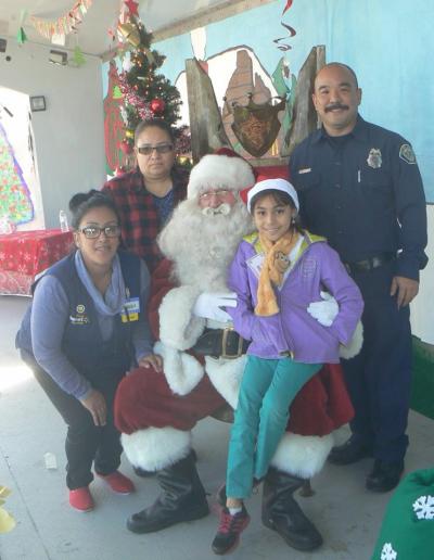 Photo courtesy: CVUSD A student and her family member have their photo taken with Santa, a Chino Police officer, and a Walmart employee at the annual Make A Child Smile event at Walmart in Chino.