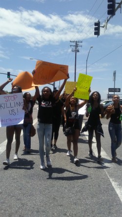 Photo by: Emily Aguilar Protesters hold signs and chant as the walk down Limonite in Eastvale.